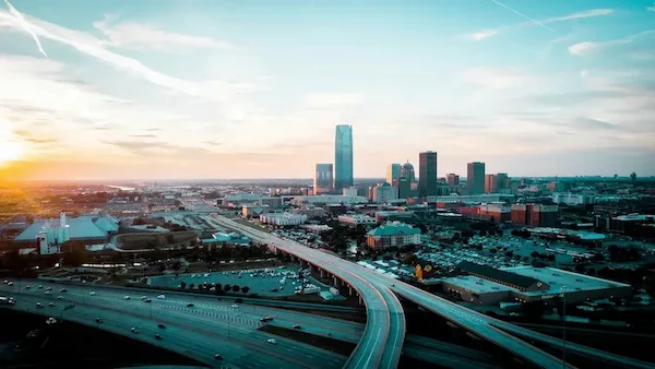 City skyline with elevated highways curving through the foreground at sunset.